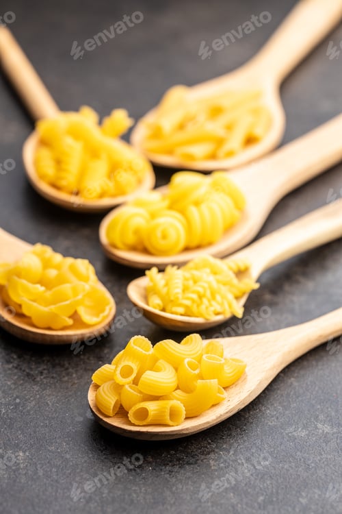Preview: Various types of raw italian pasta in wooden spoons.