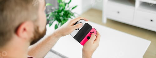 Preview: Banner man spending time at home, sitting on a couch in apartment and playing arcade car video games
