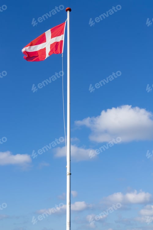 Preview: Vertical shot of Denmark flag on a flagpole against a blue sky