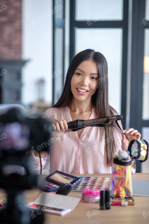 Preview: Appealing dark-eyed woman doing hairstyle in front of camera