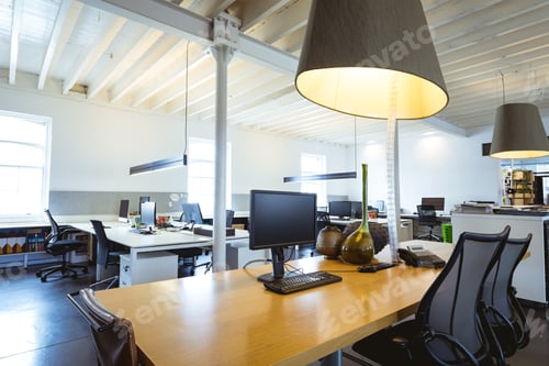 Preview: Illuminated pendant light over desk with computers in modern office
