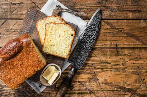 Preview: Baked sliced Brioche bread with butter. Wooden background. Top view. Copy space