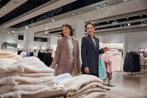 Preview: Cute girls are choosing knitted sweaters smiling while doing shopping