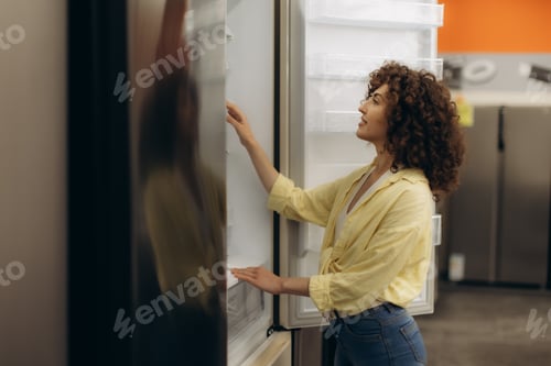 Preview: Woman Smiling While Examining a Refrigerator in an Electronics Store