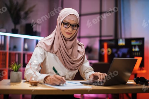 Preview: Attractive confident muslim businesswoman, office manager, wearing hijab using laptop