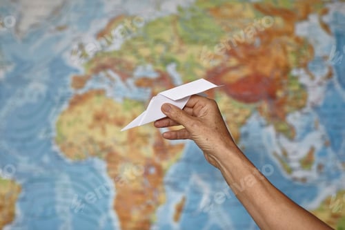 Preview: Hand holding paper plane, map of the world in background