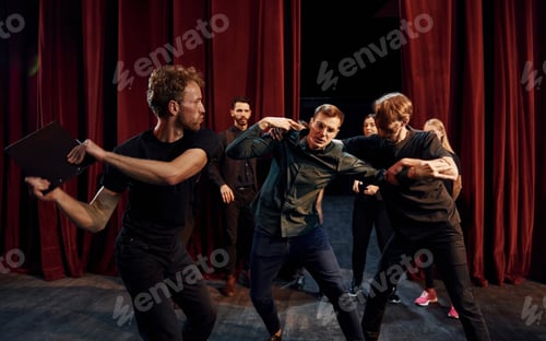 Preview: Fight scene. Group of actors in dark colored clothes on rehearsal in the theater