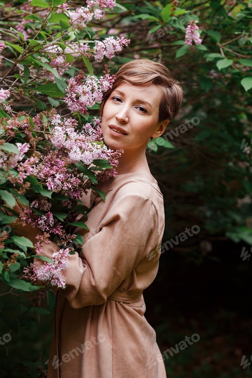 Preview: Woman hugging blooming lilac in spring garden