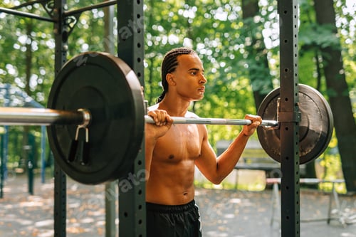 Preview: Young man leaning over weight bar after training outdoors