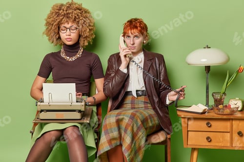 Visualização: De volta ao conceito anterior. Par de jovens mulheres afro-americanas e europeias concentradas sentadas