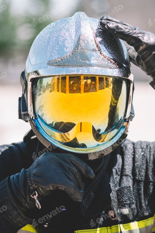 Preview: Firefighter poses with helmet looking at camera.