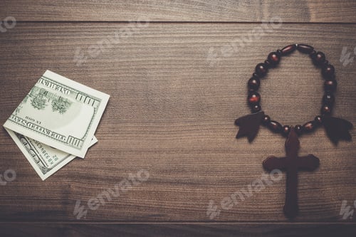 Preview: wooden cross and money on brown table background