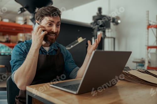 Preview: Business owner of small coffee roasting factory talking phone on his workplace