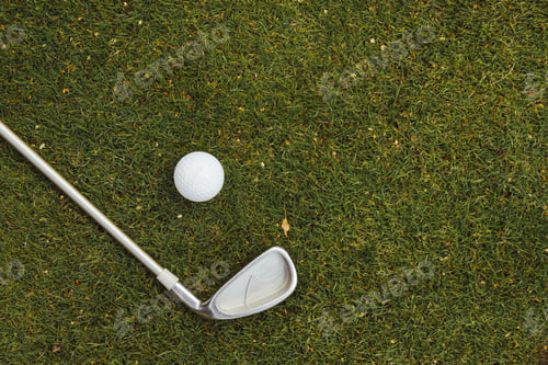 Preview: Golf ball and golf club on green grass on golf course, flat lay, top view