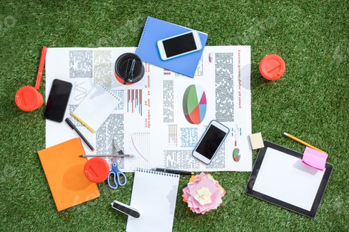 Preview: heap of business objects and office supplies laying on green grass carpet at office, business