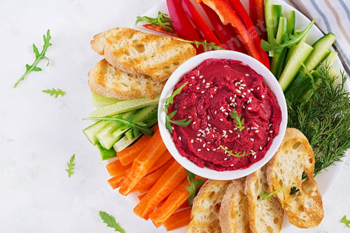 Preview: Roasted beet hummus with toast and vegetables on a light background.