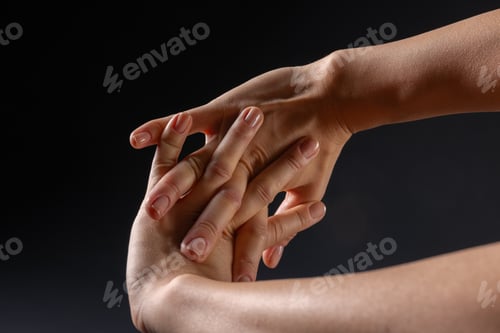 Preview: close up of female hands doing hand stretching on dark background, hand warm up concept