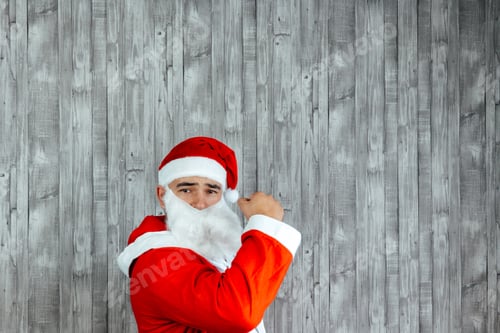 Preview: Caucasian young man dressed as Santa Claus with his fist in the air. Copy space at top