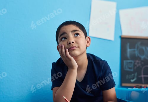 Preview: Shot of an adorable little boy looking thoughtful while completing a school assignment at his desk
