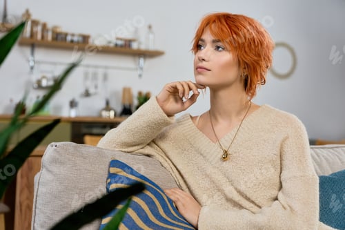 Preview: Beautiful young woman with vibrant red hair relaxing at home in cozy surroundings
