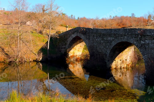 Preview: Old bridge over calm river in autumn countryside
