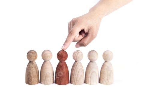 Preview: Hand picking a red wood figurine from a row of others- business strategy concept