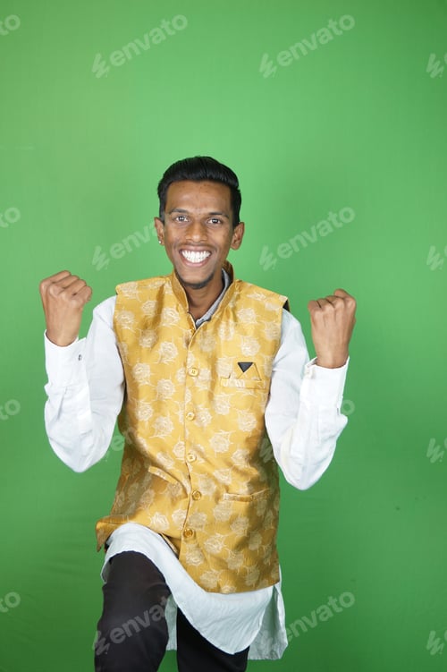 Preview: Indian boy showing his happiness with his hands up on green background