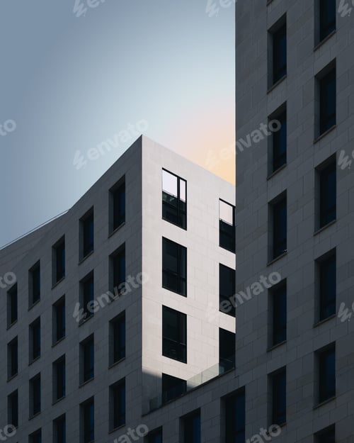 Preview: Vertical shot of a grey concrete building under the blue sky