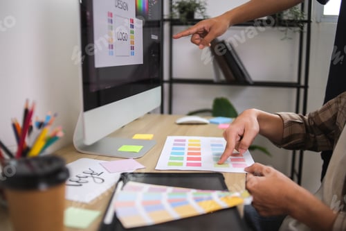Preview: Designers Reviewing Printed Color Swatch and Digital Logo Design on Computer
