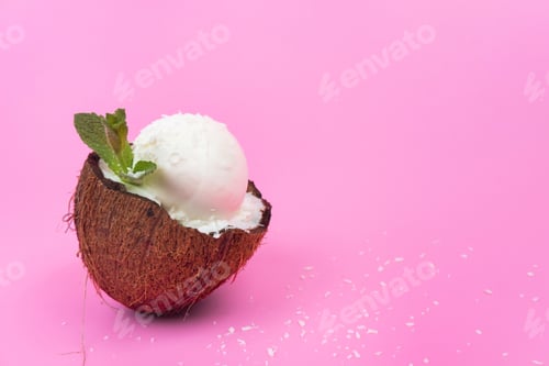 Preview: Vanilla ice cream balls in fresh coconut halves, decorated with mint leaves on a pink background