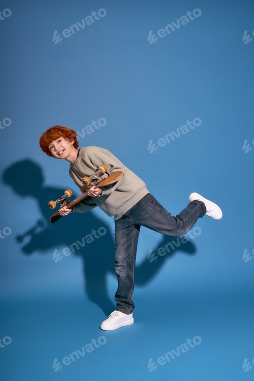 Preview: Charming young boy shows off his trendy outfit and skateboard while playfully posing on one foot