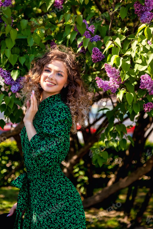 Preview: Young French woman in the park with lilac flowers outdoors