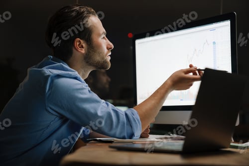 Preview: Young man working with laptop and computer while sitting at desk