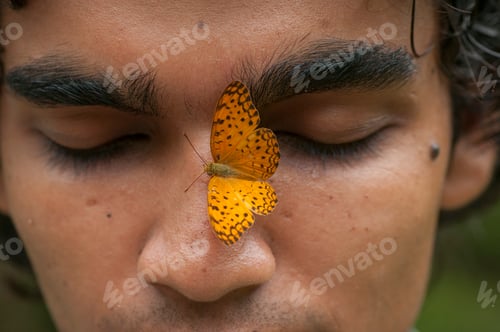 Preview: Butterfly sitting on a young man’s face, Symbiosis of man and nature.