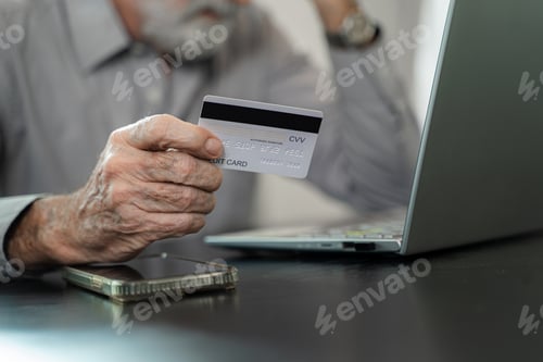 Preview: Mature man hold credit card make online payment or purchase from home.