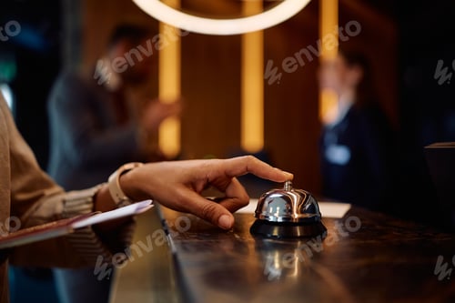 Preview: Close up of woman using service bell at hotel reception.