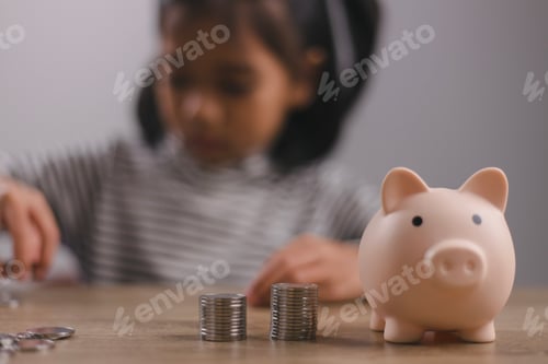 Preview: Little Asian girl saving money in a piggy bank, learning about saving, Kid save money for future