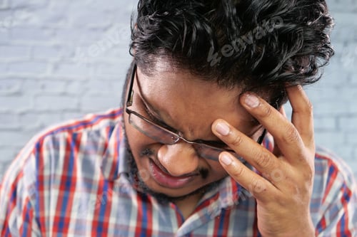 Preview: Young man frustrated and suffering headache, close up