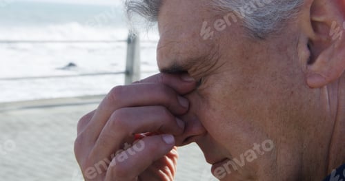 Preview: Senior, man and headache with stress on beach for heat stroke, burnout or fatigue by ocean coast. M
