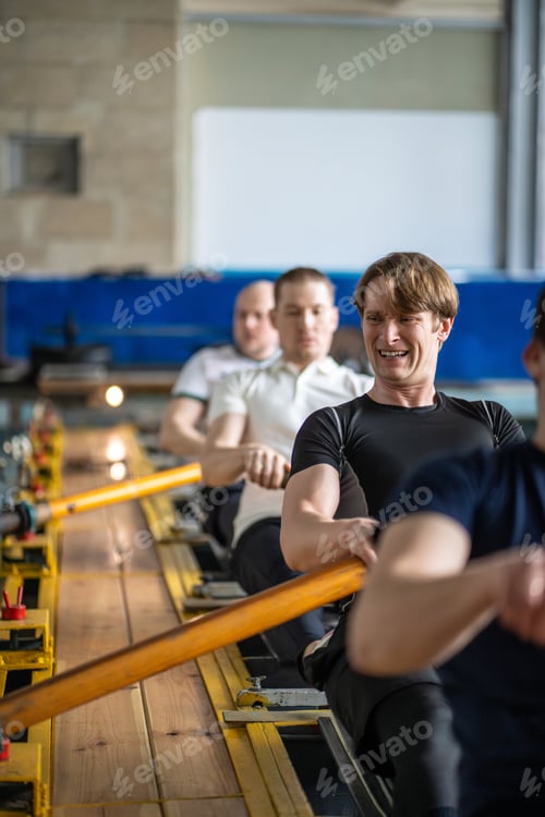 Preview: Struggling grimacing sportsmen exert on rowing simulator, paddling refining synchronized movements