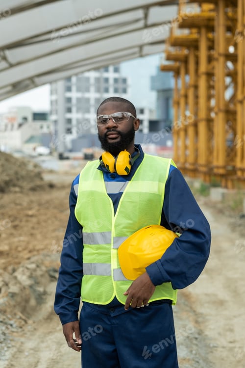 Preview: African builder in uniform standing on construction site