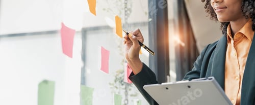 Preview: Attractive concentrated business lady in creating to-do list using multi coloured post-it sticky