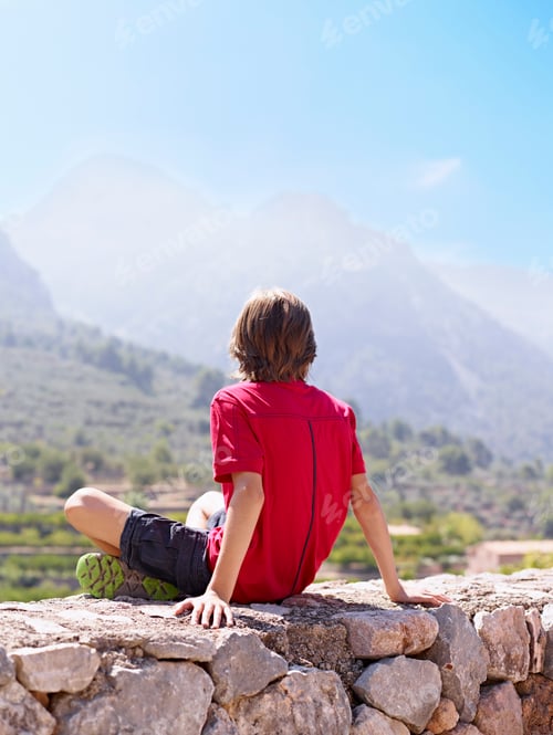 Preview: Boy sitting on stone wall gazing at view, Majorca, Spain