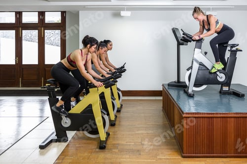 Preview: Sportswomen exercising on bikes in gym
