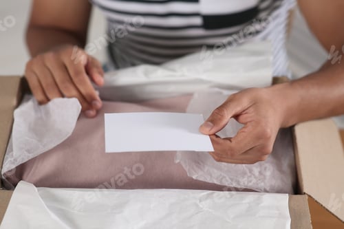 Preview: Young man holding greeting card near parcel with Christmas gift, closeup
