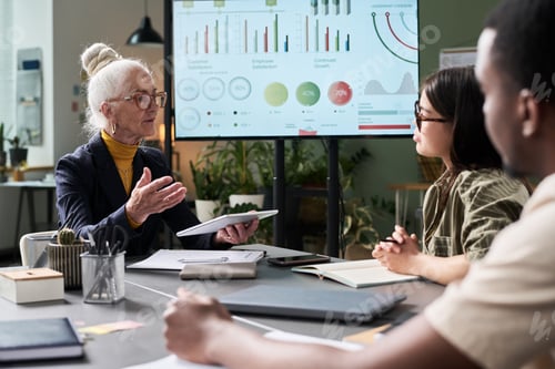 Preview: Senior Businesswoman Presenting Data to Diverse Team