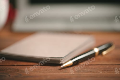 Preview: Close up of an open notepad with pen on wooden table