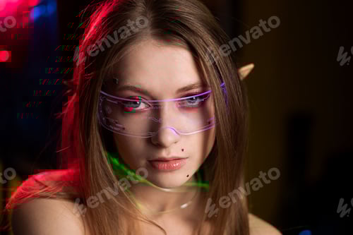 Preview: Cosplay girl in glasses with elf ears in coloured light