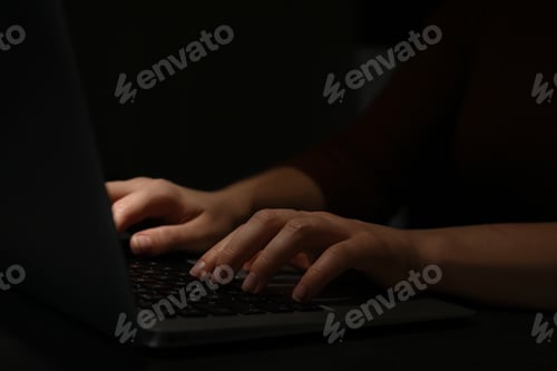 Preview: Hacker working with laptop in darkness, closeup of hands. Cyber crime