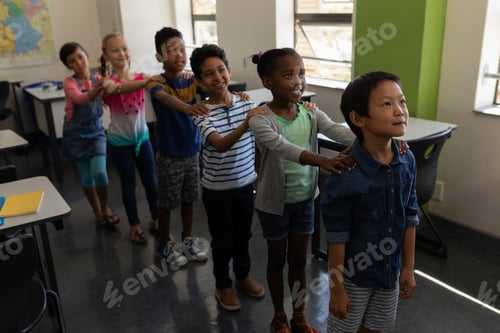 Preview: School kids standing in row with their hands on shoulder in classroom